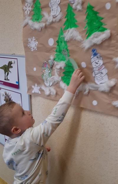 Dzieci poszukują ukrytych w sali obrazków dinozaurów