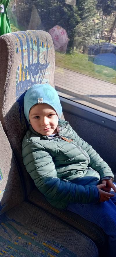 Chłopiec siedzi w autobusie i patrzy w stronę fotografującej osoby.