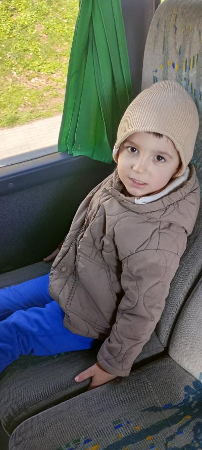 Chłopiec w autobusie, siedzący na fotelu pozuje do zdjęcia.