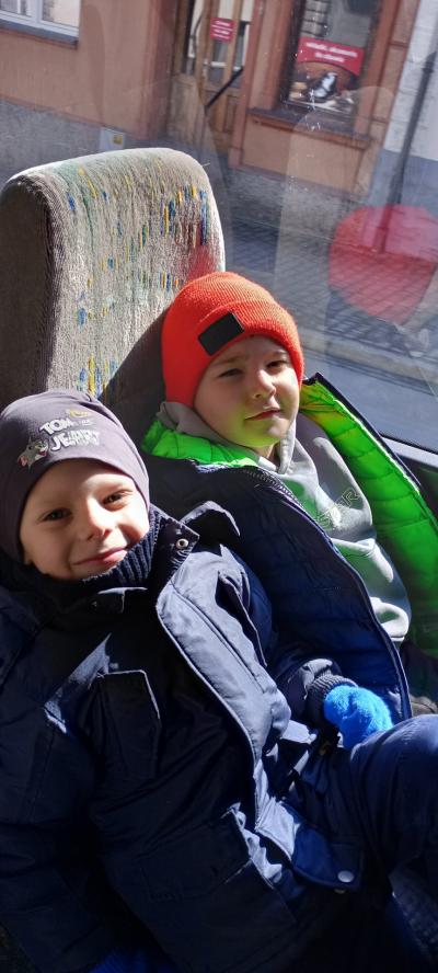 Dwóch chłopców siedzących w  autobusie i patrzących w stronę fotografującego.