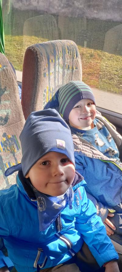 Dwóch chłopców w autobusie, siedzą uśmiechają sie do fotografa.