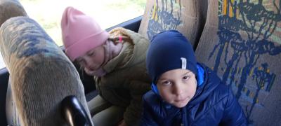 Dziewczynka i chłopiec w autobusie pozują do zdjęcia. Siedzą na fotelach