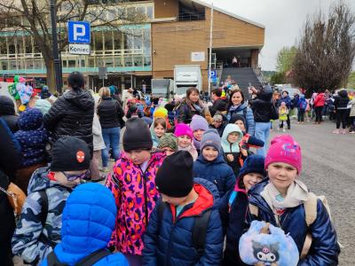 Większa grupa dzieci stojacych przed budynkiem lodowiska.