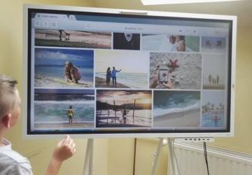 Na interaktywnym monitorze wyświetlają się miniatury zdjęć z wakacji.