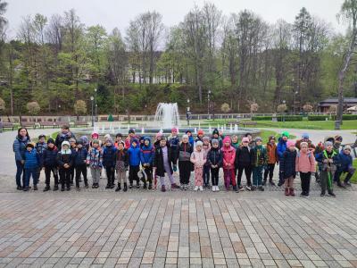 Grupa uczniów z klas pierwszych pozuje do zdjecia przy fontannie w Krynicy.